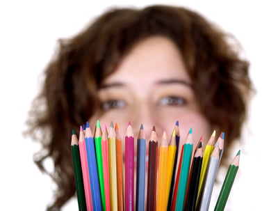 beautiful girl holding color pencils in front of her over a white background